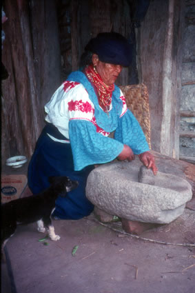 Demonstration of traditional mano and metate inside indigenous house in Otavalo area.